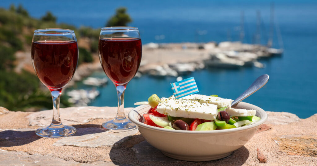 Greek food and drink, Greece flag, red wine, fruit and vegetable salad in a bowl.