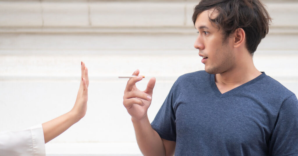 women stopping the man from smoke, cigarette in a man hand.