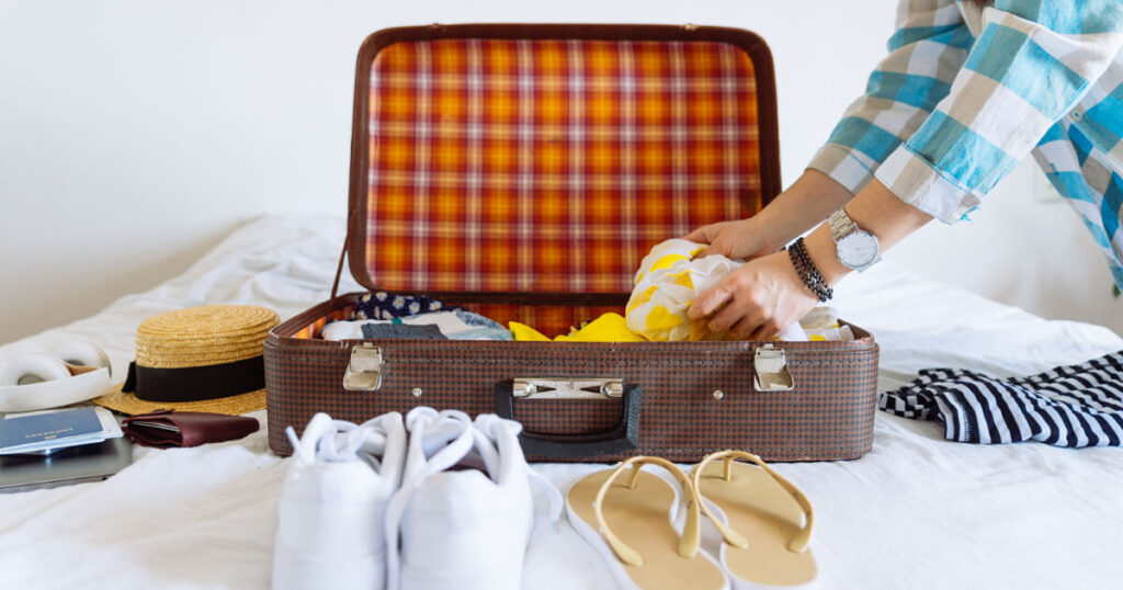 travel suitcase, blue and white checks shirt, travel shoes, flip-flop, travel hat, passport.