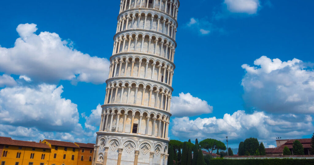 tower of Pisa, one of the seven wonders, blue sky, yellow houses.