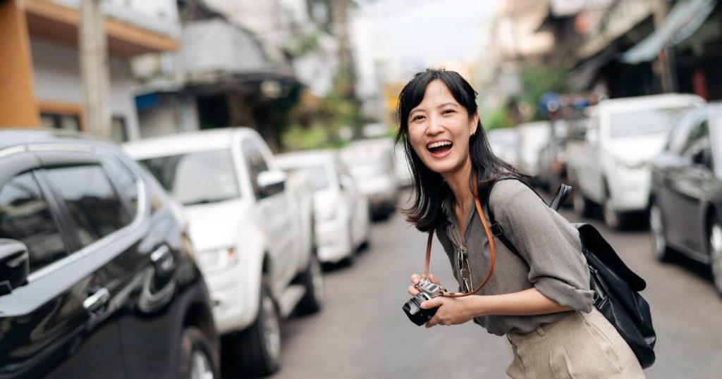 photography in Japan, Japanese girl with Camara, Japan travel restrictions, Japanese cars in background.