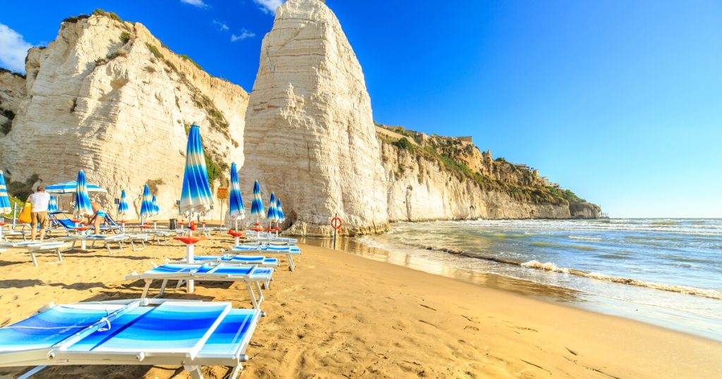 Italy beach, big rocks, umbrella on beach, blue water, less crowd in Italy, The best time to visit Italy.